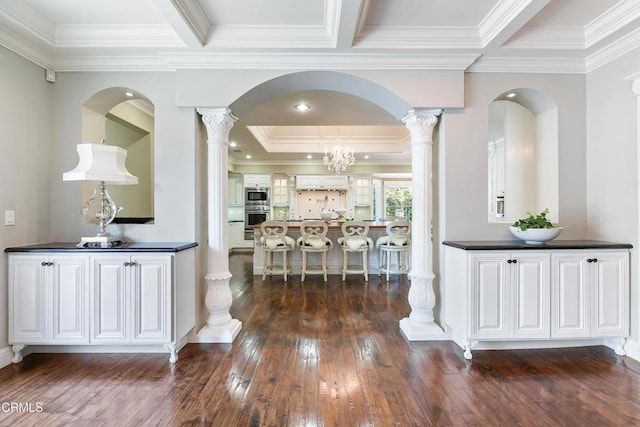 hall featuring decorative columns, ornamental molding, and a chandelier