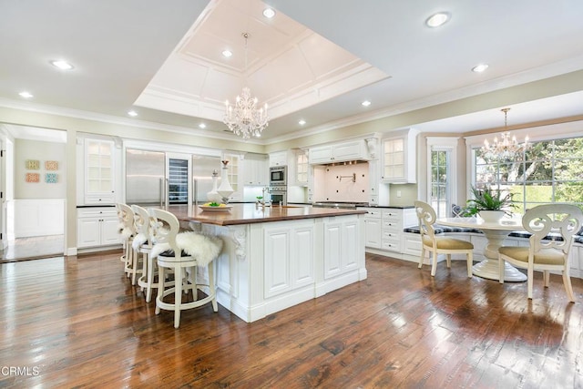 kitchen with white cabinetry, a chandelier, a raised ceiling, and a spacious island