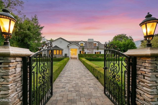 gate at dusk featuring a lawn