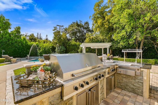 view of patio / terrace featuring pool water feature, area for grilling, and exterior kitchen