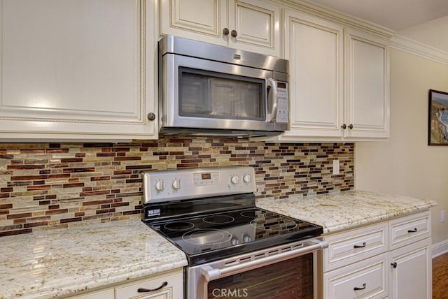 kitchen featuring decorative backsplash, light stone countertops, stainless steel appliances, and cream cabinets