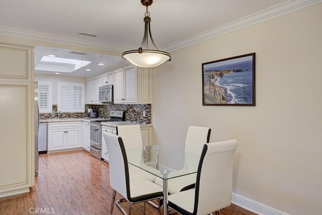 dining area with wood-type flooring, sink, and ornamental molding