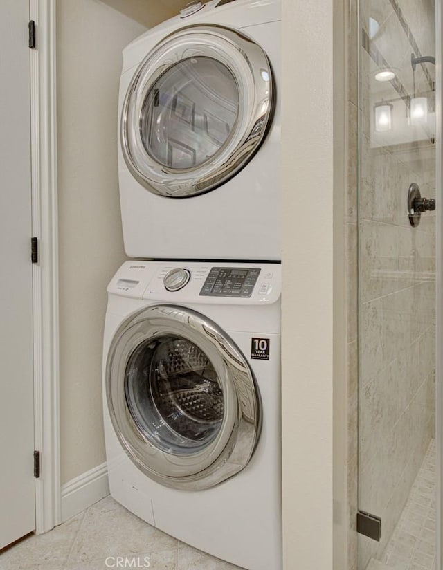 washroom with stacked washer / drying machine and light tile patterned flooring