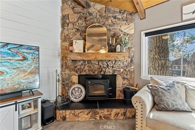 living room featuring wood ceiling, a wood stove, beamed ceiling, and carpet flooring