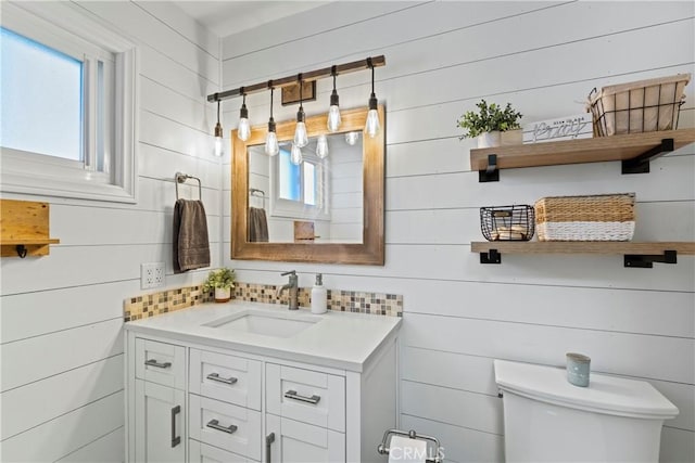 bathroom with toilet, vanity, and wooden walls