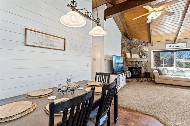 dining area with ceiling fan, wood-type flooring, beamed ceiling, wooden walls, and wooden ceiling