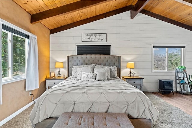 bedroom featuring a wood stove, multiple windows, and vaulted ceiling with beams