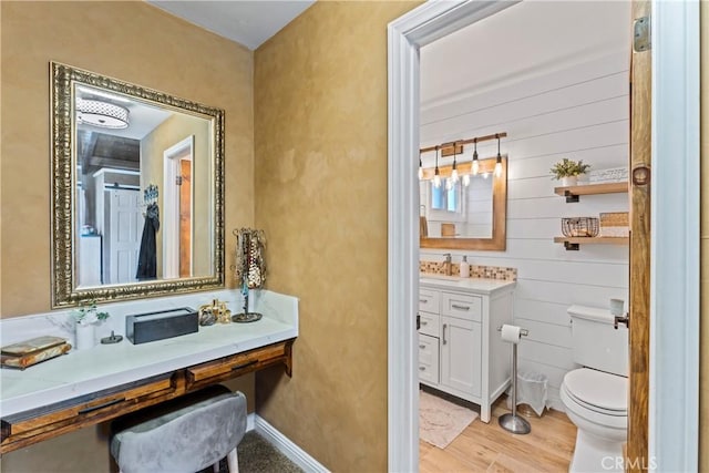 bathroom with hardwood / wood-style floors, toilet, vanity, and wood walls