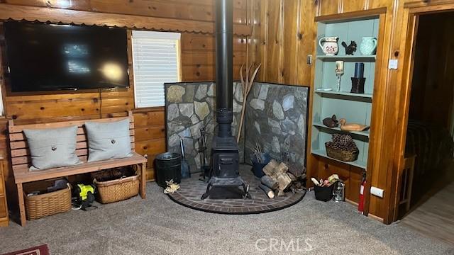 interior space featuring built in features, carpet, a wood stove, and wood walls