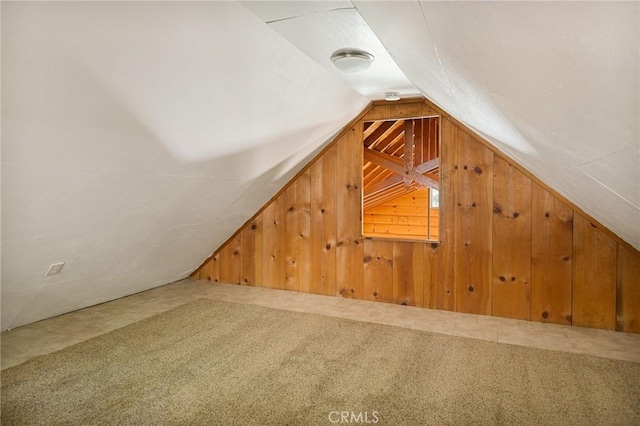 bonus room with carpet, vaulted ceiling, and wooden walls