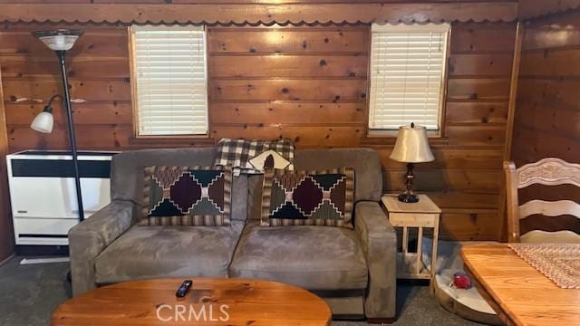 sitting room featuring wood walls and dark colored carpet