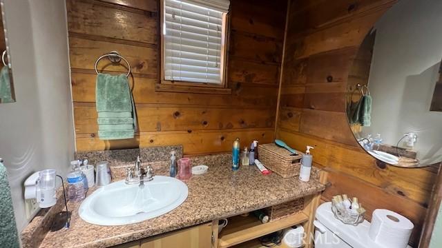 bathroom featuring toilet, vanity, wood walls, and water heater