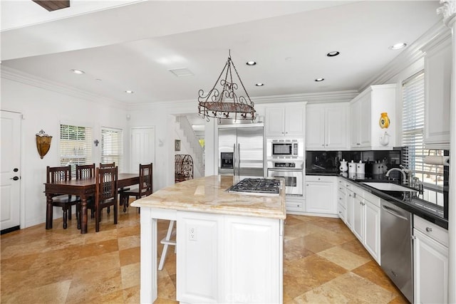 kitchen featuring ornamental molding, dark stone counters, built in appliances, a kitchen island, and sink