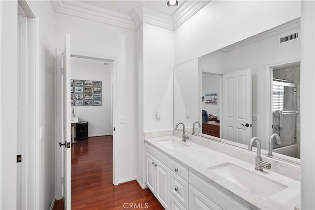 bathroom with crown molding, walk in shower, hardwood / wood-style floors, and vanity