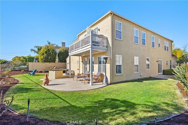 back of property featuring a lawn, a patio area, and a balcony