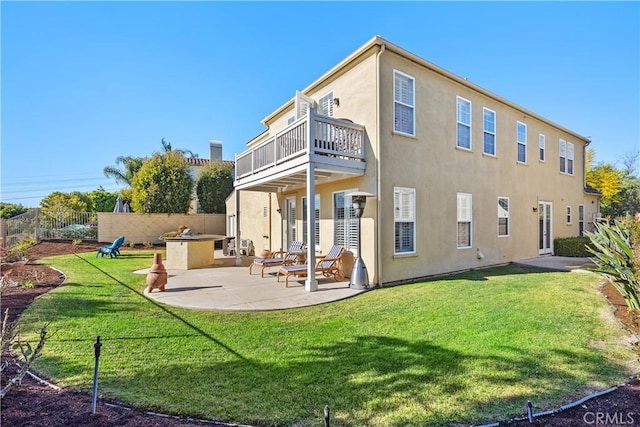rear view of house with a yard, a patio, fence, and stucco siding