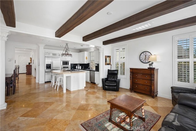 living room with decorative columns, sink, a wealth of natural light, and beamed ceiling