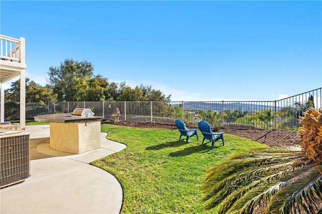 view of yard featuring a patio, exterior kitchen, central AC unit, and a fenced backyard