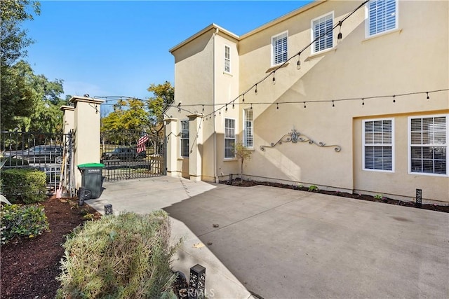 view of side of property featuring fence, a gate, and stucco siding