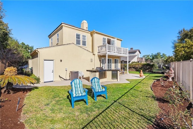 rear view of property featuring a balcony, exterior kitchen, cooling unit, a patio, and a yard