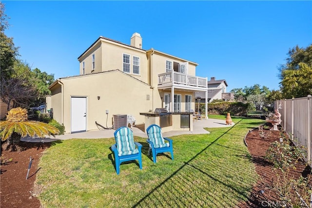 rear view of house with a yard, a patio, exterior kitchen, and a balcony