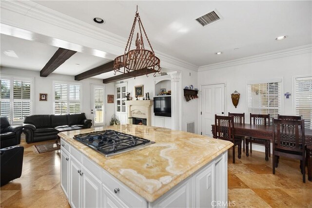 kitchen featuring white cabinets, beamed ceiling, stainless steel gas cooktop, and a kitchen island