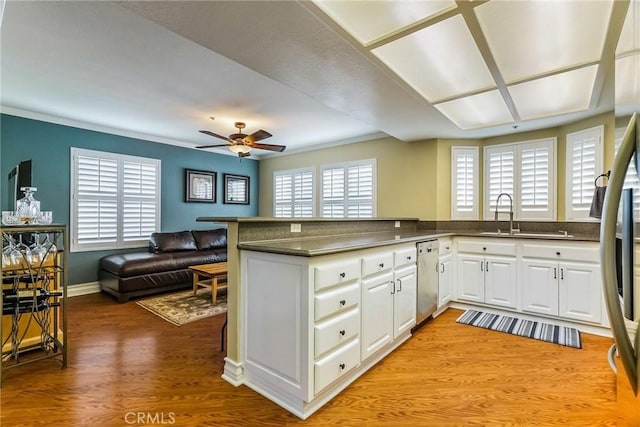 kitchen with appliances with stainless steel finishes, sink, white cabinets, and kitchen peninsula