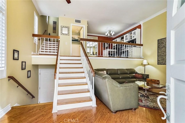 living room featuring hardwood / wood-style flooring, crown molding, and ceiling fan with notable chandelier