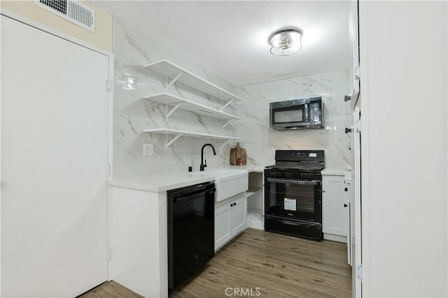 kitchen featuring hardwood / wood-style floors, black appliances, decorative backsplash, sink, and white cabinetry