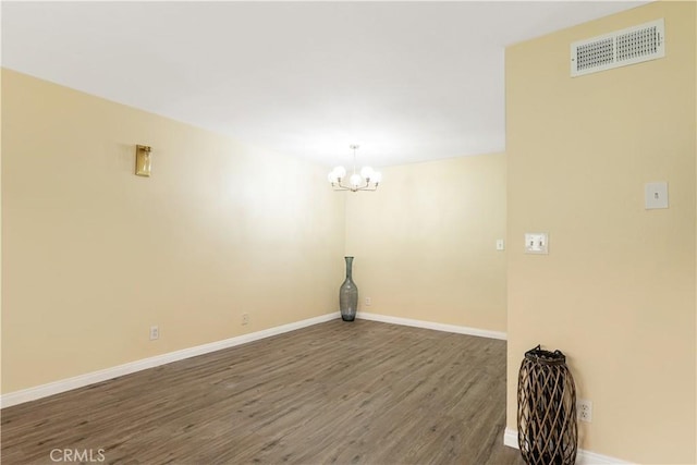 empty room featuring dark hardwood / wood-style floors and a notable chandelier