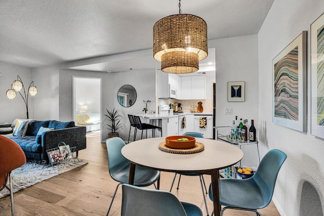 dining area featuring a textured ceiling and light hardwood / wood-style floors