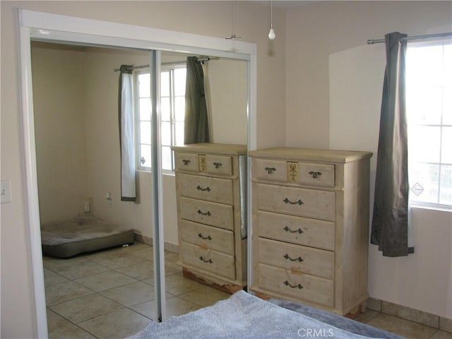 unfurnished bedroom with a closet, light tile patterned flooring, and multiple windows