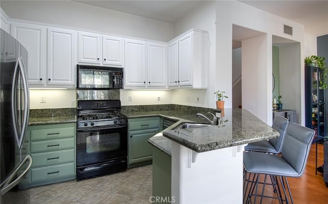 kitchen with white cabinets, black appliances, sink, kitchen peninsula, and a breakfast bar