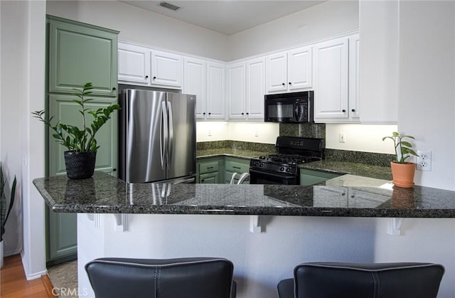 kitchen with a kitchen breakfast bar, white cabinetry, kitchen peninsula, and black appliances