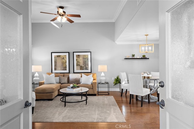 living room with ceiling fan with notable chandelier, dark wood-type flooring, and crown molding