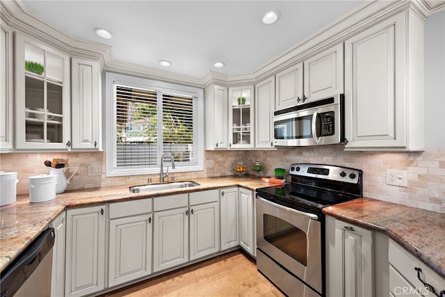 kitchen featuring stainless steel appliances, white cabinetry, sink, and light stone counters