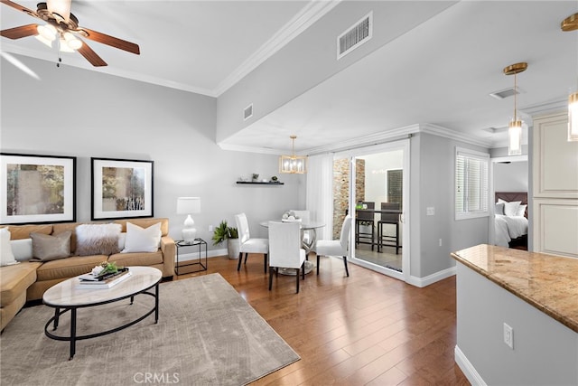 living room with ceiling fan with notable chandelier, hardwood / wood-style floors, and ornamental molding