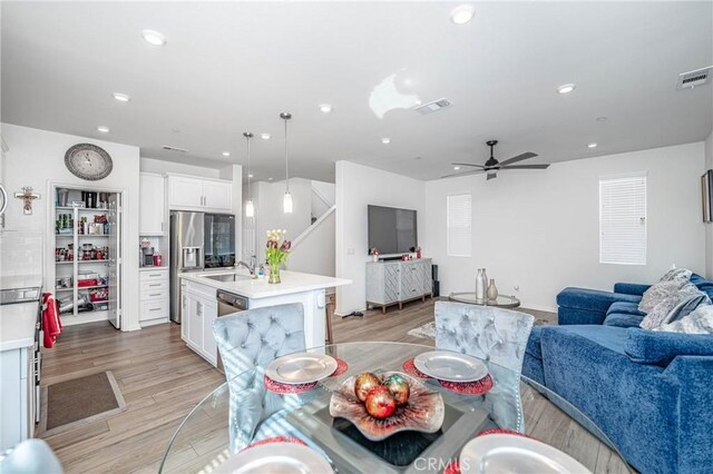 dining room with ceiling fan, light hardwood / wood-style floors, and sink