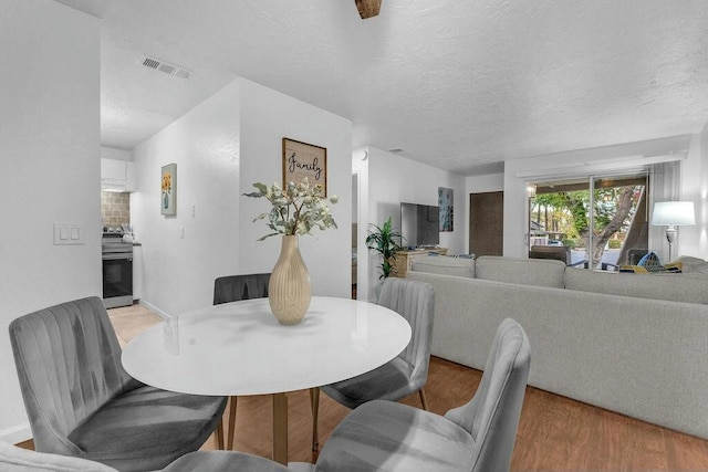 dining room with wood-type flooring and a textured ceiling