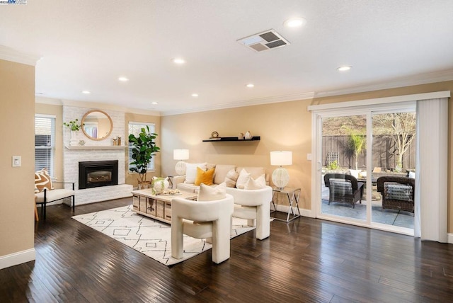 living room with dark wood-type flooring, crown molding, and a brick fireplace