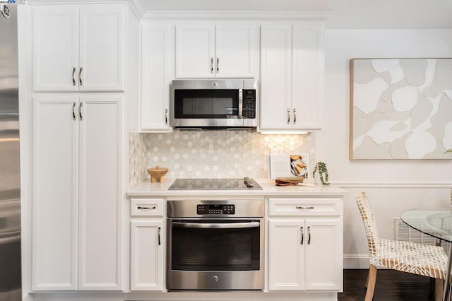 kitchen with decorative backsplash, stainless steel appliances, and white cabinets