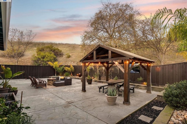 patio terrace at dusk featuring a gazebo and an outdoor living space with a fire pit