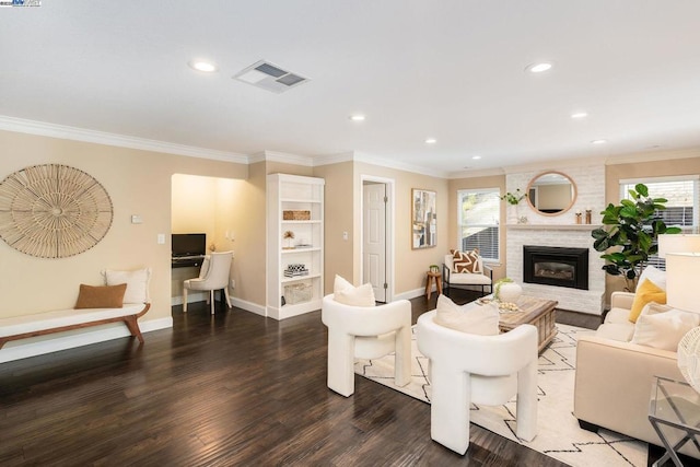 living room with dark hardwood / wood-style flooring, plenty of natural light, crown molding, and a fireplace