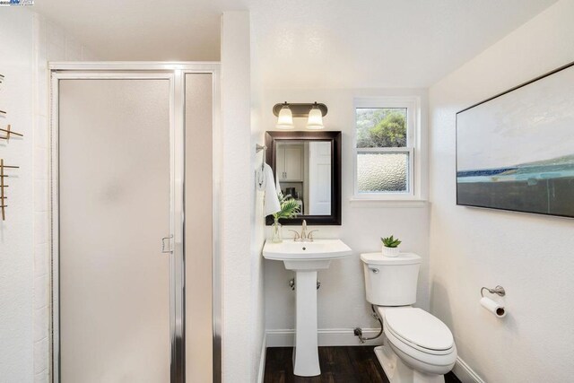 bathroom featuring toilet, wood-type flooring, and walk in shower