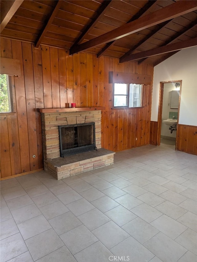 unfurnished living room with wood ceiling, a stone fireplace, lofted ceiling with beams, and wood walls