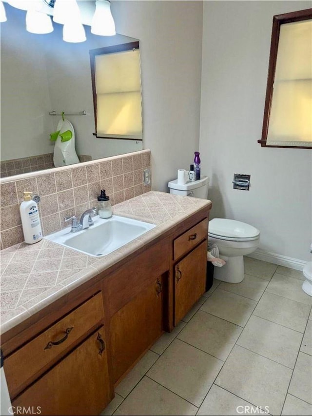 bathroom with vanity, toilet, tile patterned flooring, and backsplash