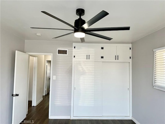 unfurnished bedroom with ceiling fan, dark hardwood / wood-style flooring, and a closet