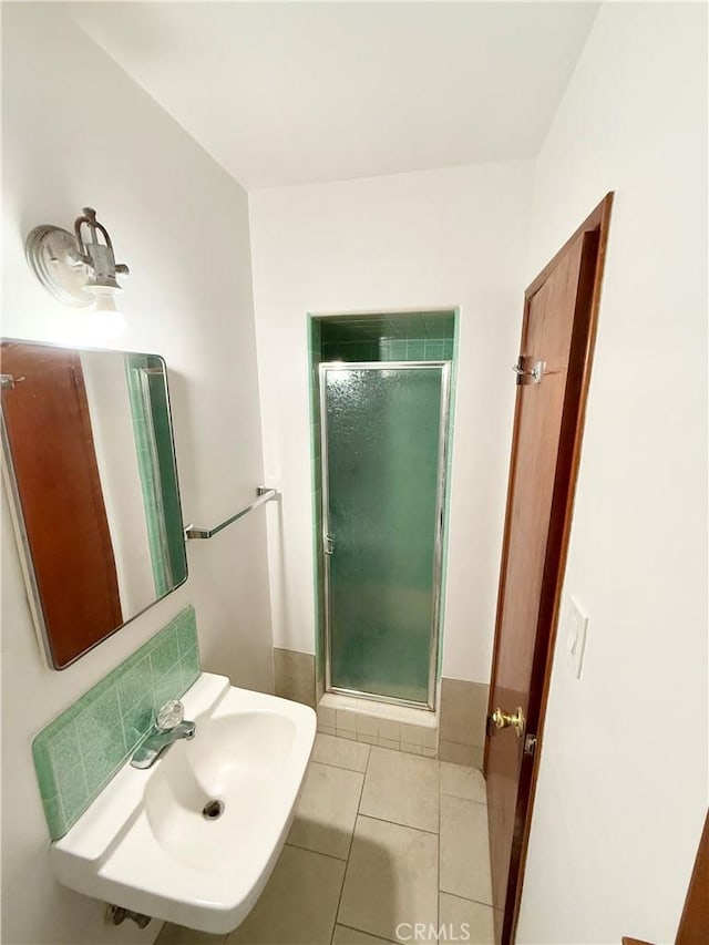 bathroom with an enclosed shower, sink, and tile patterned flooring