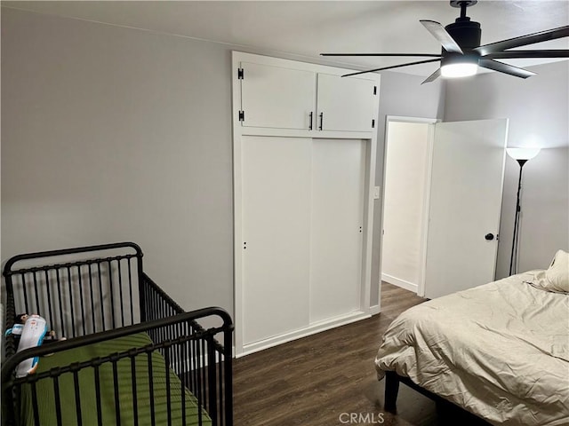 bedroom with dark wood-type flooring, ceiling fan, and a closet