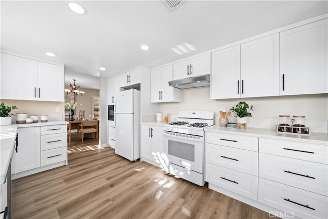 kitchen featuring white cabinets, an inviting chandelier, white appliances, and light hardwood / wood-style floors